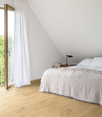 une chambre avec un sol stratifié beige et une fenêtre ouverte